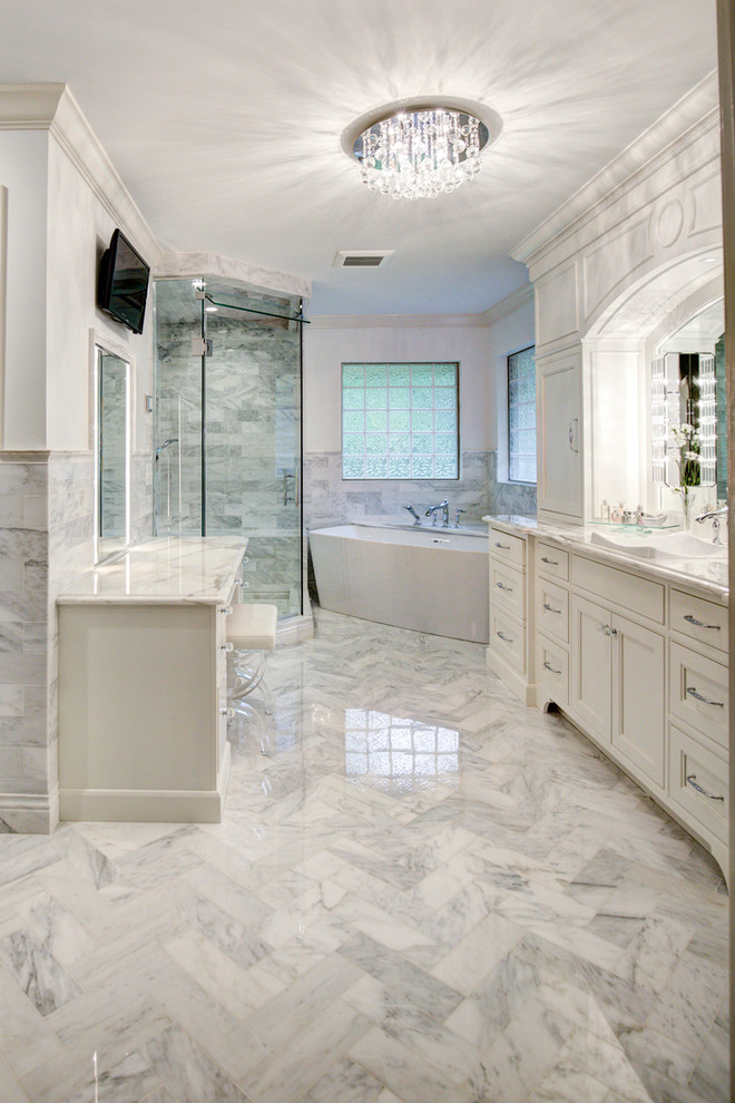 Cette image montre une grande salle de bain principale design avec un placard à porte affleurante, des portes de placard blanches, une baignoire indépendante, une douche d'angle, un carrelage gris, un carrelage blanc, du carrelage en marbre, un mur blanc, un sol en marbre, une vasque, un plan de toilette en marbre, un sol gris et une cabine de douche à porte battante.