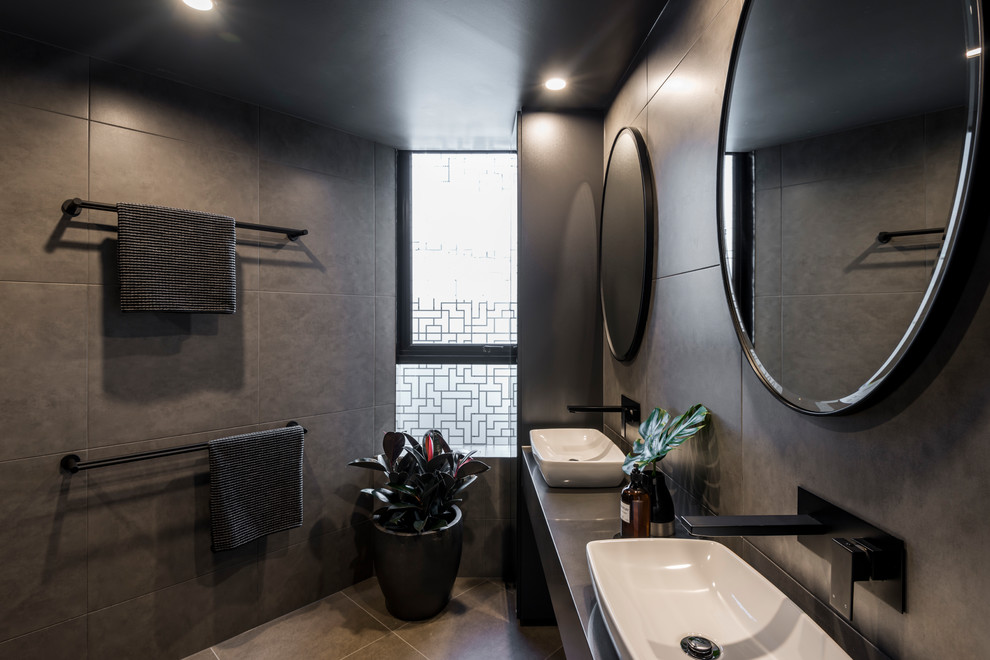 Cette image montre une salle de bain bohème de taille moyenne avec un carrelage gris, des carreaux de céramique, un mur gris, un sol en carrelage de céramique, une vasque et un sol gris.