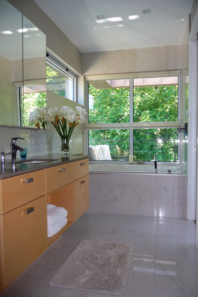 Immagine di una stanza da bagno design con ante lisce, ante in legno chiaro, piastrelle grigie, pareti grigie e pavimento con piastrelle in ceramica