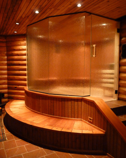 Cette photo montre un grand sauna montagne avec une douche d'angle, un mur marron, un sol en carrelage de céramique, un sol marron et une cabine de douche à porte battante.