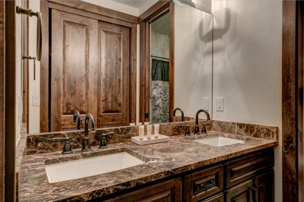 Imagen de cuarto de baño rústico de tamaño medio con armarios con paneles con relieve, puertas de armario de madera oscura, paredes blancas, lavabo bajoencimera y encimera de granito