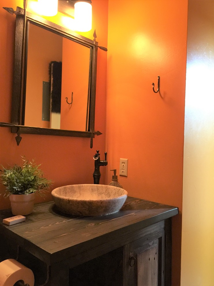 Inspiration för mellanstora rustika badrum med dusch, med möbel-liknande, bruna skåp, en toalettstol med separat cisternkåpa, orange väggar, mörkt trägolv, ett fristående handfat, träbänkskiva och brunt golv
