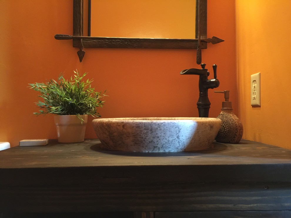 Réalisation d'une salle d'eau chalet de taille moyenne avec un placard en trompe-l'oeil, des portes de placard marrons, WC séparés, un mur orange, une vasque, un plan de toilette en bois, un sol en bois brun et un sol multicolore.