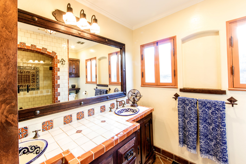Свежая идея для дизайна: ванная комната среднего размера в средиземноморском стиле с фасадами с выступающей филенкой, коричневыми фасадами, ванной в нише, душем над ванной, оранжевой плиткой, керамической плиткой, белыми стенами, полом из терракотовой плитки, накладной раковиной, столешницей из плитки и душем с распашными дверями - отличное фото интерьера