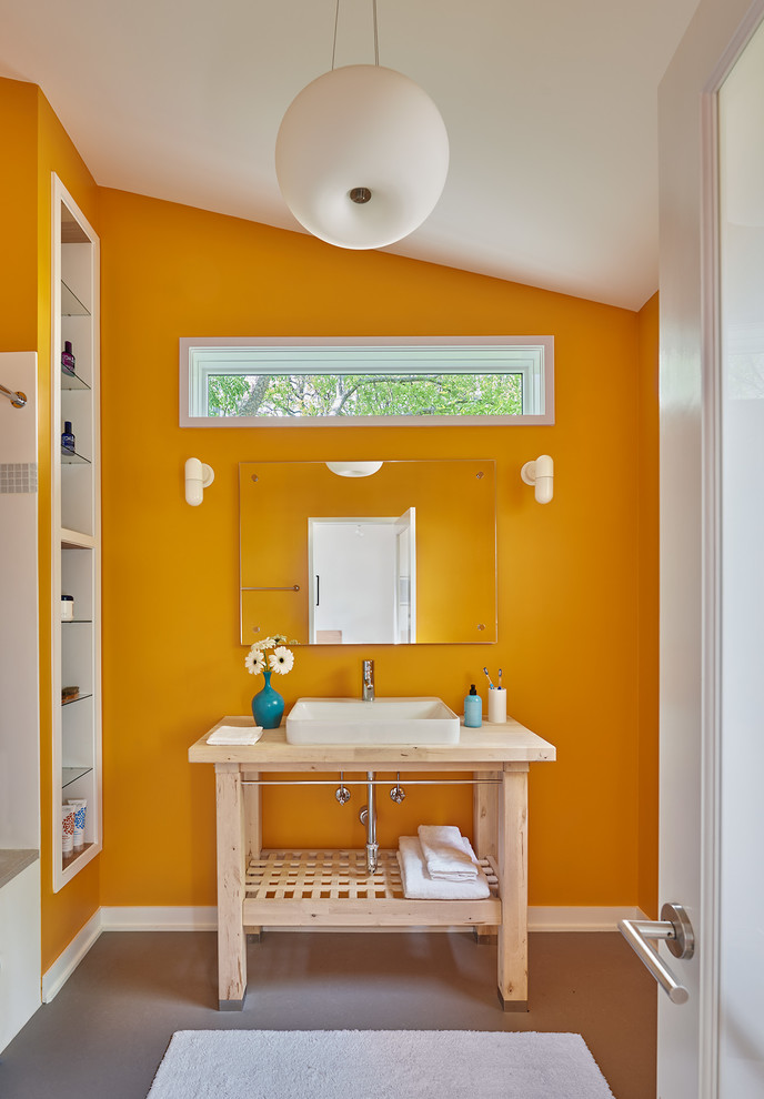 На фото: ванная комната в современном стиле с открытыми фасадами, светлыми деревянными фасадами, желтыми стенами, бетонным полом, настольной раковиной, столешницей из дерева, серым полом и бежевой столешницей