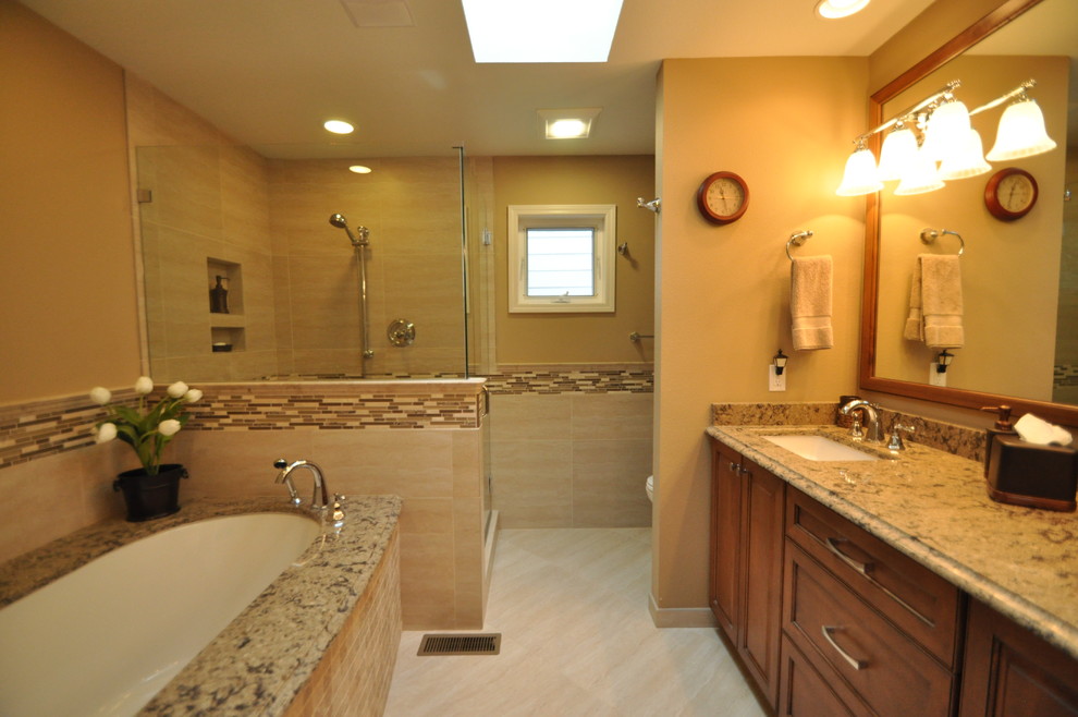 Inspiration for a mid-sized timeless master beige tile and porcelain tile porcelain tile corner shower remodel in Seattle with an undermount sink, raised-panel cabinets, medium tone wood cabinets, granite countertops, an undermount tub, a two-piece toilet and beige walls