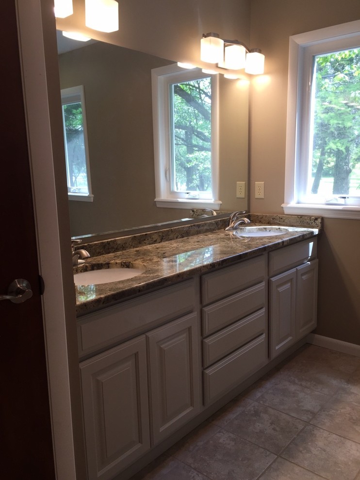 This is an example of a medium sized traditional ensuite bathroom in Columbus with a submerged sink, raised-panel cabinets, beige cabinets, granite worktops, an alcove shower, a two-piece toilet, beige tiles, porcelain tiles, green walls, porcelain flooring, beige floors and a hinged door.