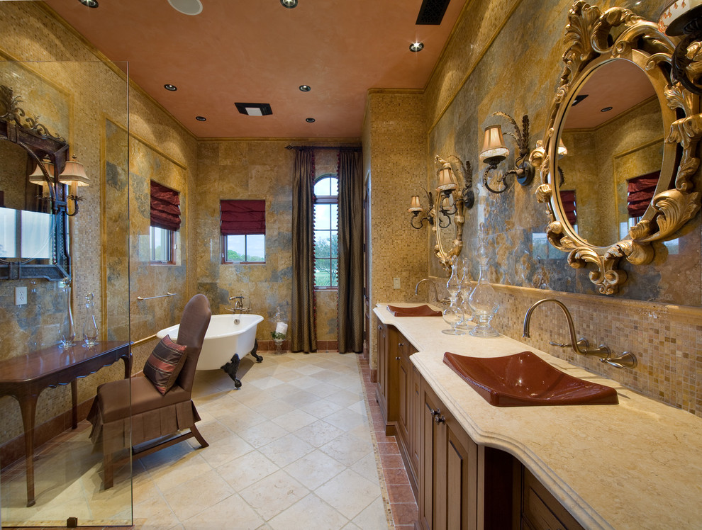 Пример оригинального дизайна: большая главная ванная комната в средиземноморском стиле с накладной раковиной, ванной на ножках, фасадами с выступающей филенкой, темными деревянными фасадами, столешницей из гранита, душем в нише, раздельным унитазом, разноцветной плиткой, каменной плиткой, желтыми стенами и полом из травертина