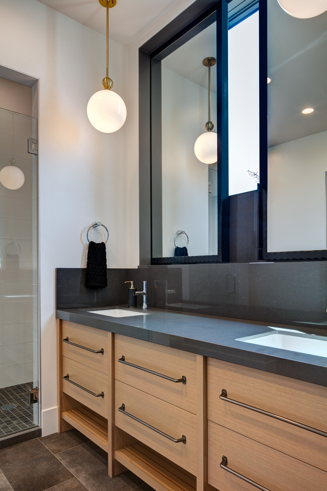 Example of a mid-sized minimalist white tile and ceramic tile ceramic tile and gray floor alcove shower design in Salt Lake City with flat-panel cabinets, light wood cabinets, a one-piece toilet, white walls, an undermount sink, quartz countertops, a hinged shower door and black countertops