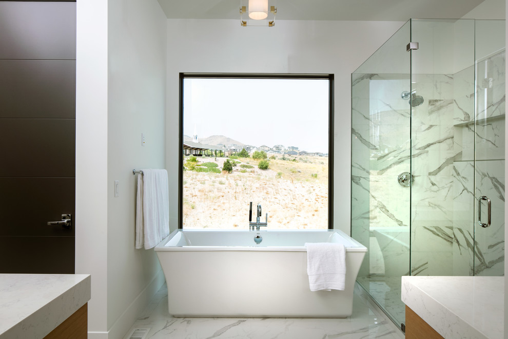 Стильный дизайн: главная ванная комната среднего размера в современном стиле с плоскими фасадами, светлыми деревянными фасадами, отдельно стоящей ванной, угловым душем, унитазом-моноблоком, белой плиткой, керамической плиткой, белыми стенами, полом из керамической плитки, врезной раковиной, столешницей из искусственного кварца, белым полом, душем с распашными дверями и белой столешницей - последний тренд