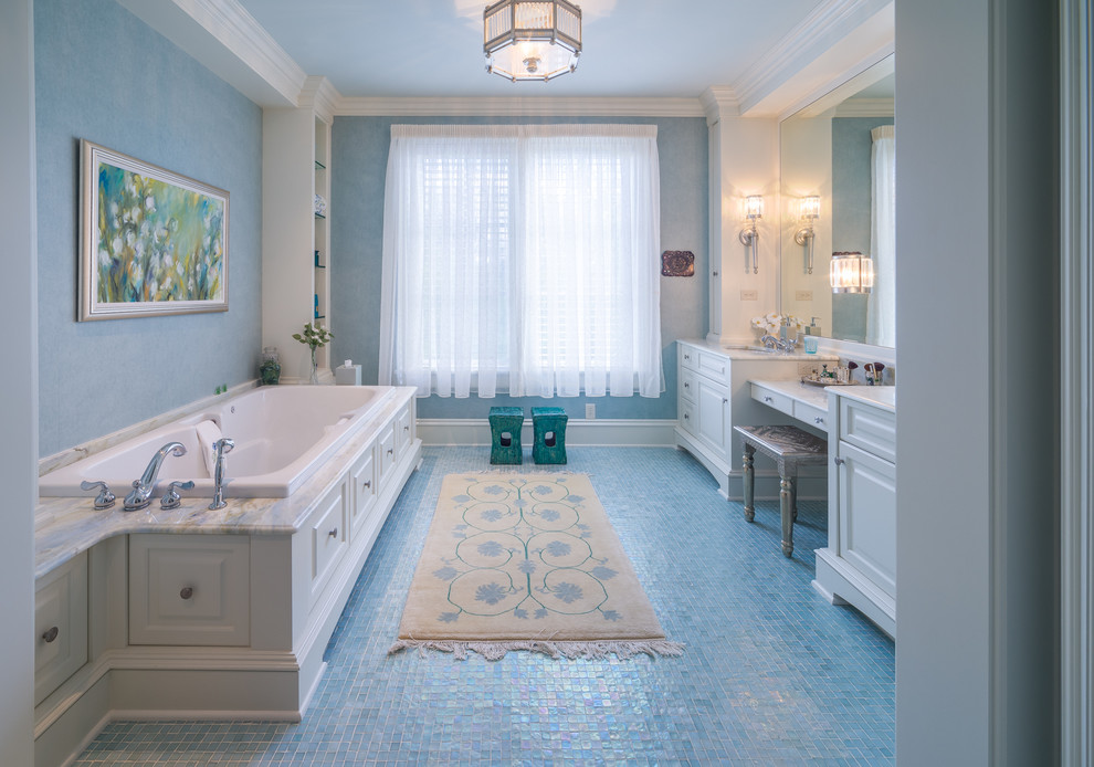Inredning av ett klassiskt badrum, med ett undermonterad handfat, luckor med upphöjd panel, vita skåp, ett platsbyggt badkar, blå väggar, mosaikgolv och blått golv