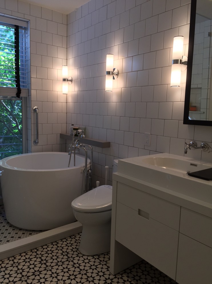 Example of a mid-sized minimalist master white tile and ceramic tile cement tile floor bathroom design in New York with flat-panel cabinets, white cabinets, a bidet, white walls, solid surface countertops and a trough sink