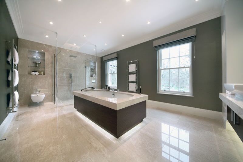 Photo of a large modern family bathroom in Dorset with a built-in sink, freestanding cabinets, dark wood cabinets, marble worktops, a built-in bath, a walk-in shower, a wall mounted toilet, beige tiles, ceramic tiles, grey walls and ceramic flooring.