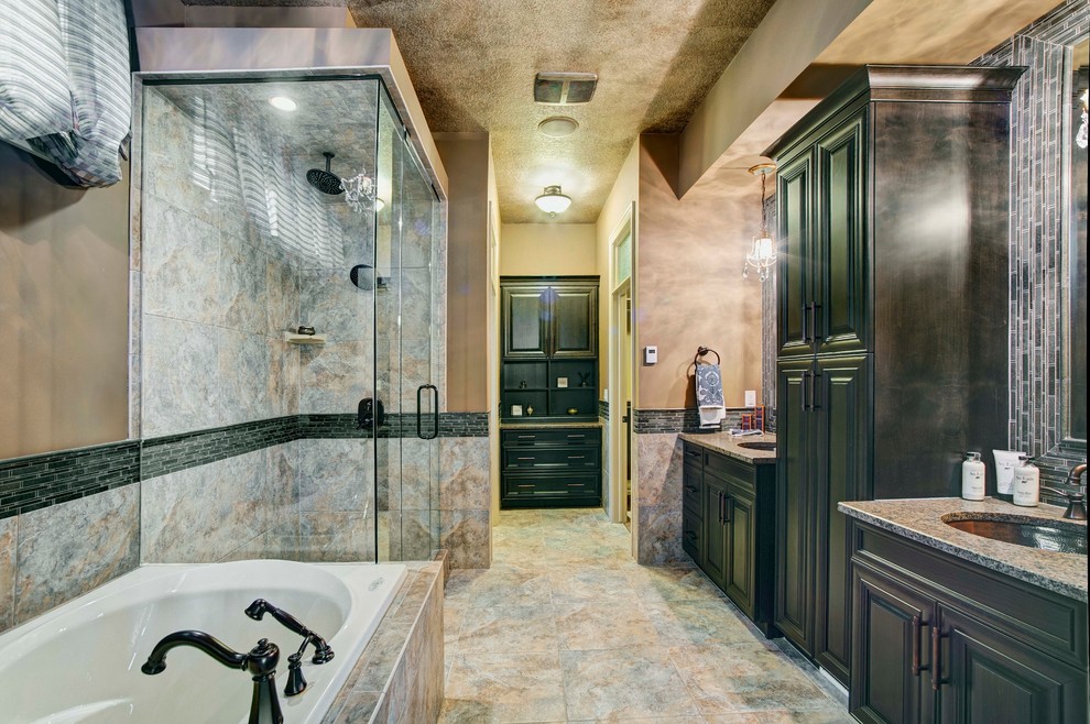 Cette photo montre une grande salle de bain principale rétro avec un placard avec porte à panneau surélevé, une baignoire indépendante, une douche d'angle, un carrelage noir, un carrelage noir et blanc, un carrelage gris, un mur gris, tomettes au sol, un lavabo encastré, un plan de toilette en granite et des portes de placard marrons.
