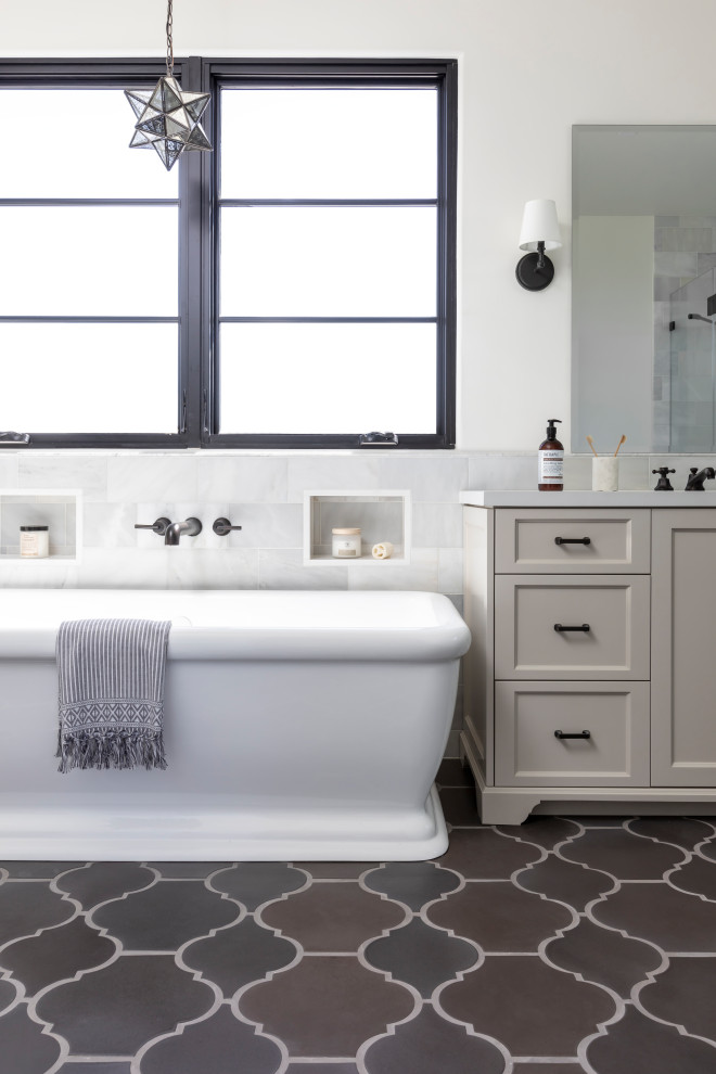 На фото: ванная комната в средиземноморском стиле с фасадами с утопленной филенкой, серыми фасадами, отдельно стоящей ванной, белыми стенами, коричневым полом, белой столешницей, встроенной тумбой, нишей и тумбой под одну раковину с