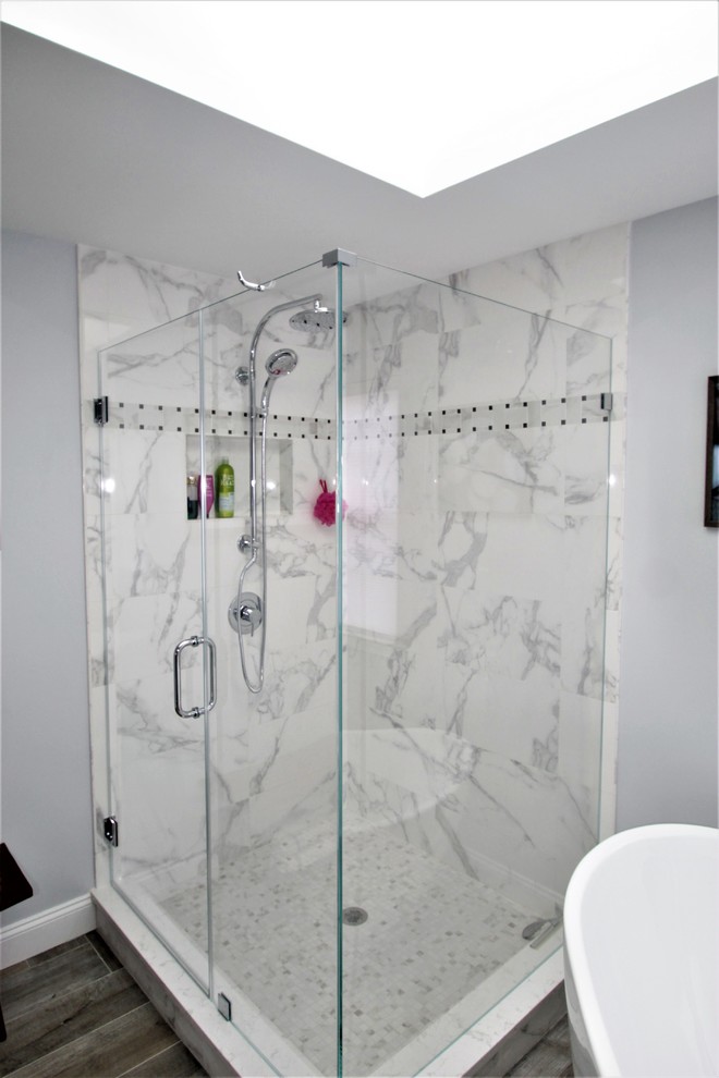 Photo of a medium sized traditional ensuite bathroom in New York with flat-panel cabinets, grey cabinets, a freestanding bath, a corner shower, a one-piece toilet, multi-coloured tiles, porcelain tiles, grey walls, porcelain flooring, a submerged sink and quartz worktops.