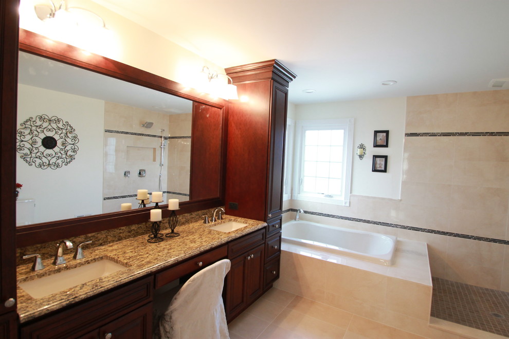 This is an example of a large traditional ensuite bathroom in New York with a submerged sink, raised-panel cabinets, medium wood cabinets, granite worktops, a built-in bath, a two-piece toilet, beige tiles, ceramic tiles, beige walls and porcelain flooring.