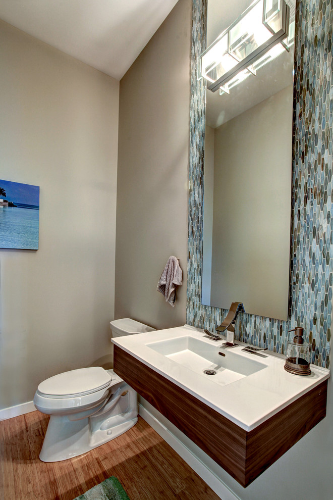 На фото: ванная комната среднего размера в современном стиле с монолитной раковиной, раздельным унитазом, синей плиткой, коричневой плиткой, серой плиткой, белой плиткой, стеклянной плиткой, серыми стенами, полом из бамбука и душевой кабиной