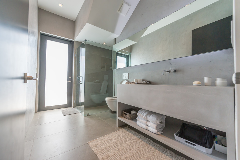 This is an example of a large contemporary ensuite bathroom in Miami with flat-panel cabinets, grey cabinets, an alcove shower, a wall mounted toilet, grey walls, concrete flooring, a trough sink, concrete worktops, grey floors and a hinged door.