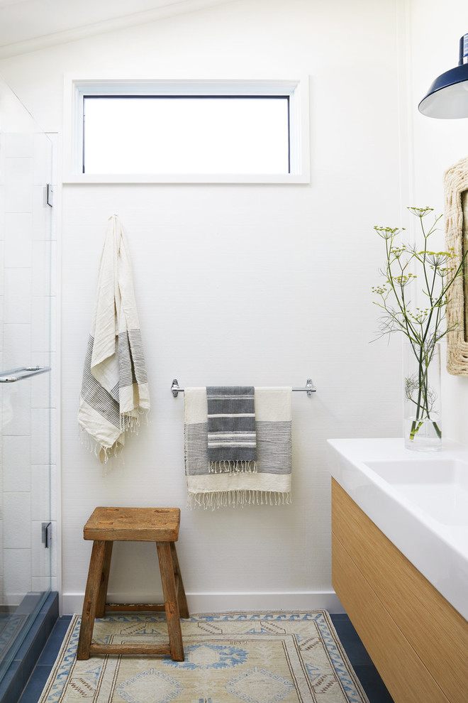 Ejemplo de cuarto de baño marinero con armarios con paneles lisos, puertas de armario de madera clara, baldosas y/o azulejos blancos, paredes blancas, lavabo tipo consola y suelo azul