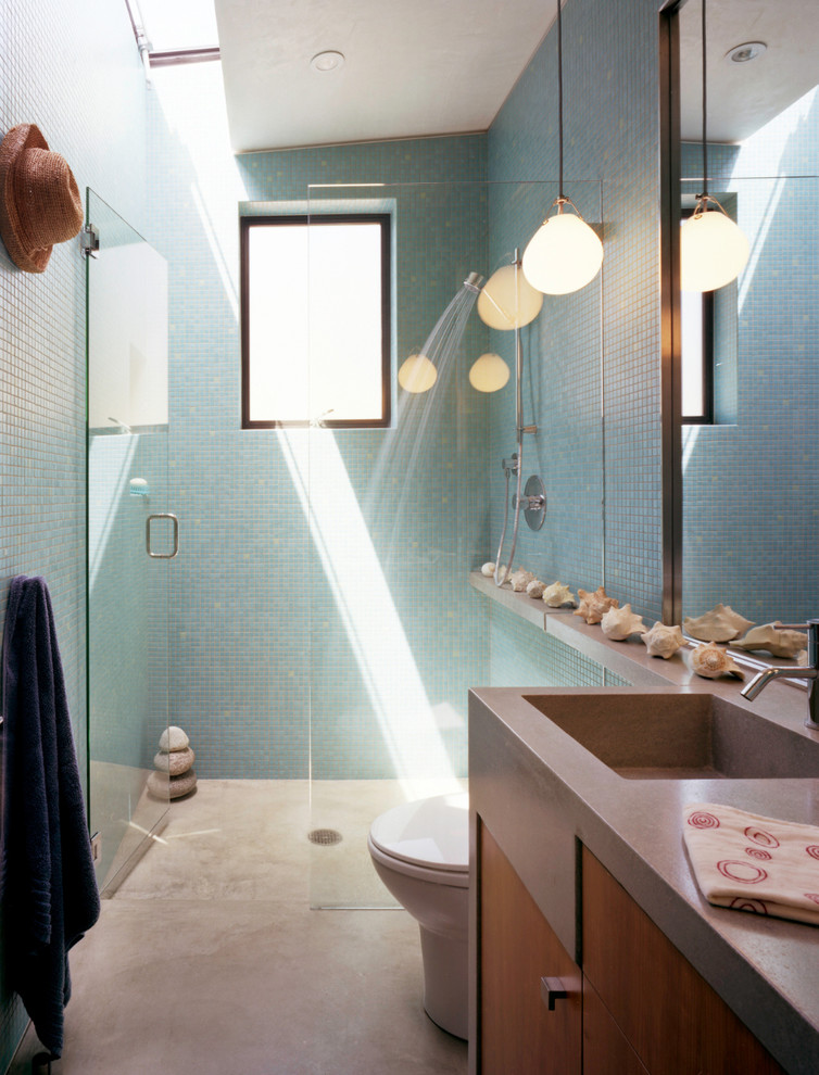 Стильный дизайн: ванная комната среднего размера в морском стиле с плоскими фасадами, фасадами цвета дерева среднего тона, душем без бортиков, унитазом-моноблоком, керамической плиткой, белыми стенами, бетонным полом, душевой кабиной, монолитной раковиной и синей плиткой - последний тренд