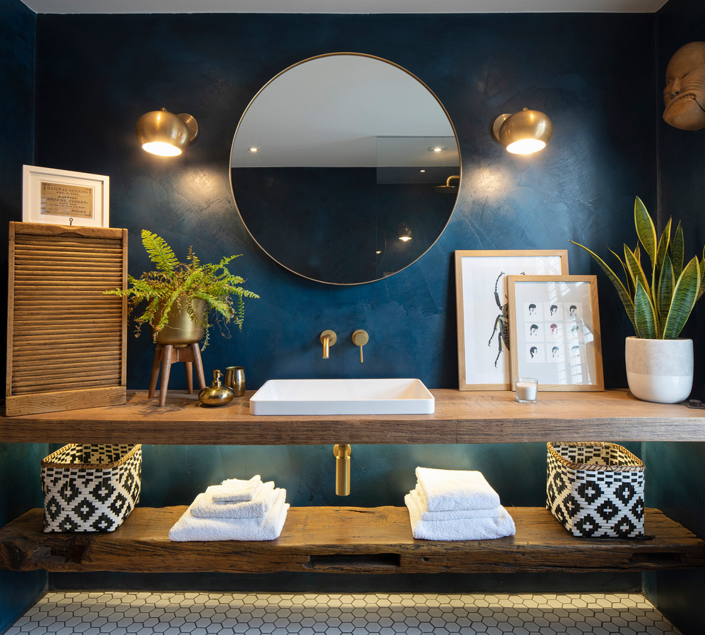 Eclectic bathroom in London with open cabinets, brown cabinets, a wall mounted toilet, blue walls, porcelain flooring, a built-in sink, wooden worktops, white floors, an open shower and brown worktops.