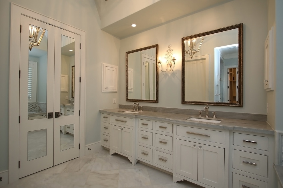 Immagine di una grande stanza da bagno padronale chic con ante a filo, pavimento in marmo, lavabo da incasso, top in pietra calcarea e vasca sottopiano