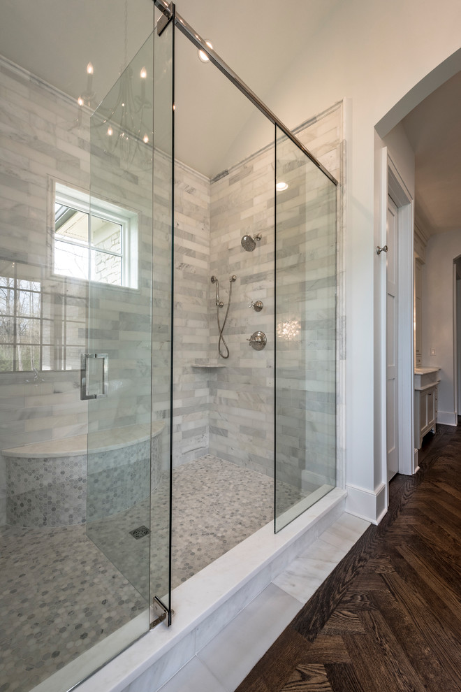 Large traditional ensuite wet room bathroom in Cincinnati with beaded cabinets, white cabinets, a freestanding bath, a one-piece toilet, white tiles, marble tiles, white walls, dark hardwood flooring, a built-in sink, marble worktops, brown floors and a hinged door.