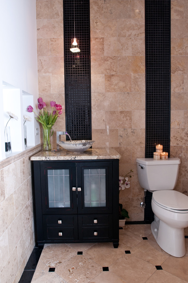 Cette image montre une salle d'eau méditerranéenne en bois foncé de taille moyenne avec un placard à porte vitrée, WC séparés, un carrelage beige, un carrelage noir, mosaïque, un mur beige, un sol en carrelage de céramique, une vasque, un plan de toilette en granite et un sol beige.