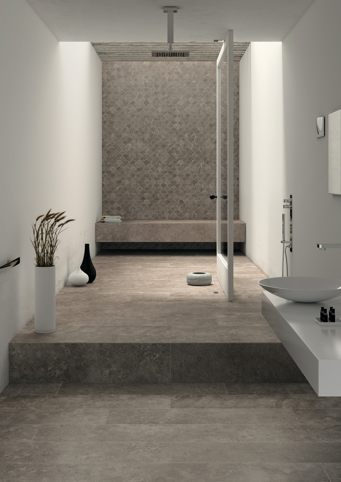 Cette image montre une salle de bain design avec un carrelage gris, un sol en carrelage de porcelaine, des portes de placard blanches, une douche ouverte, des carreaux de porcelaine, un mur blanc, une vasque et un plan de toilette en surface solide.