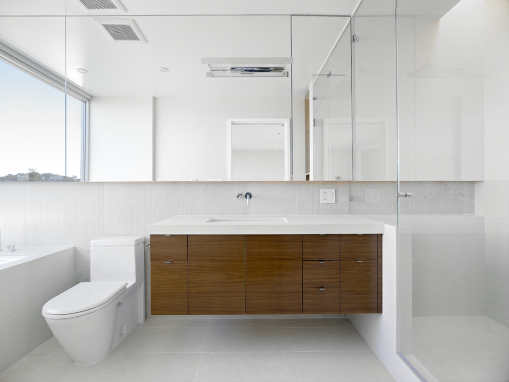 Ispirazione per una stanza da bagno minimalista di medie dimensioni con lavabo sottopiano, ante lisce, ante in legno scuro, WC monopezzo, vasca sottopiano, doccia ad angolo, pareti bianche, top in quarzo composito e top bianco