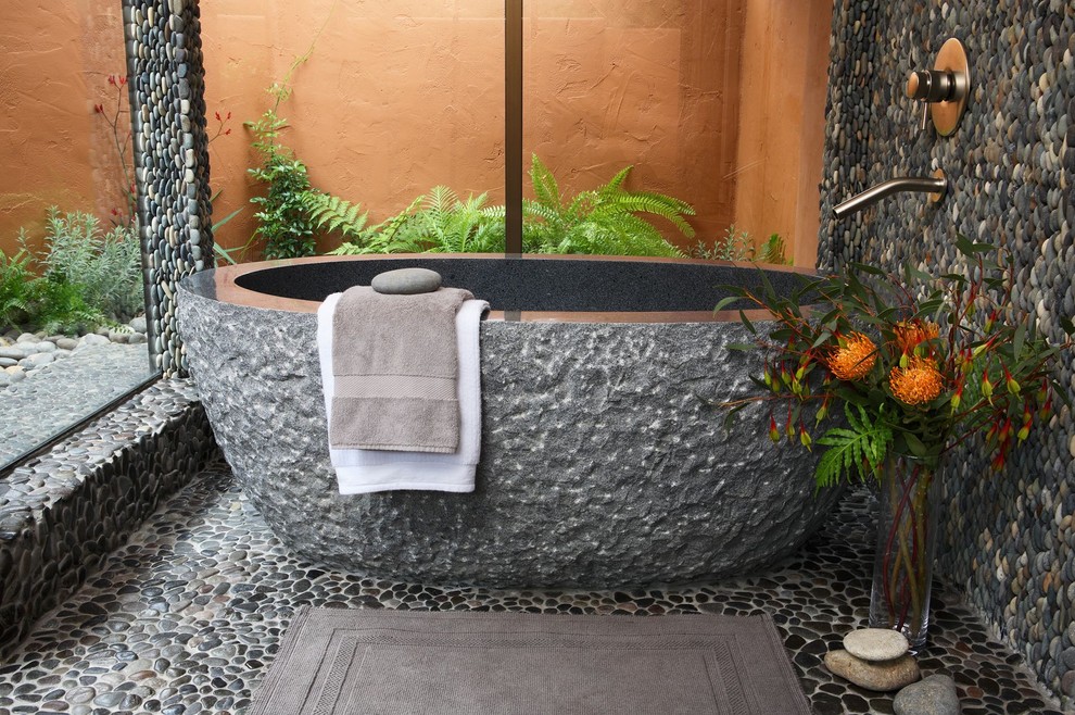 Example of a tuscan pebble tile pebble tile floor freestanding bathtub design in San Francisco
