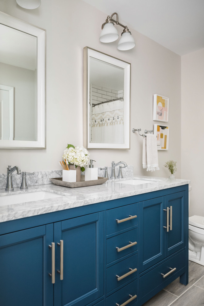 Inspiration for a large timeless kids' white tile and porcelain tile porcelain tile and gray floor bathroom remodel in Charlotte with shaker cabinets, blue cabinets, a two-piece toilet, gray walls, an undermount sink, marble countertops and gray countertops