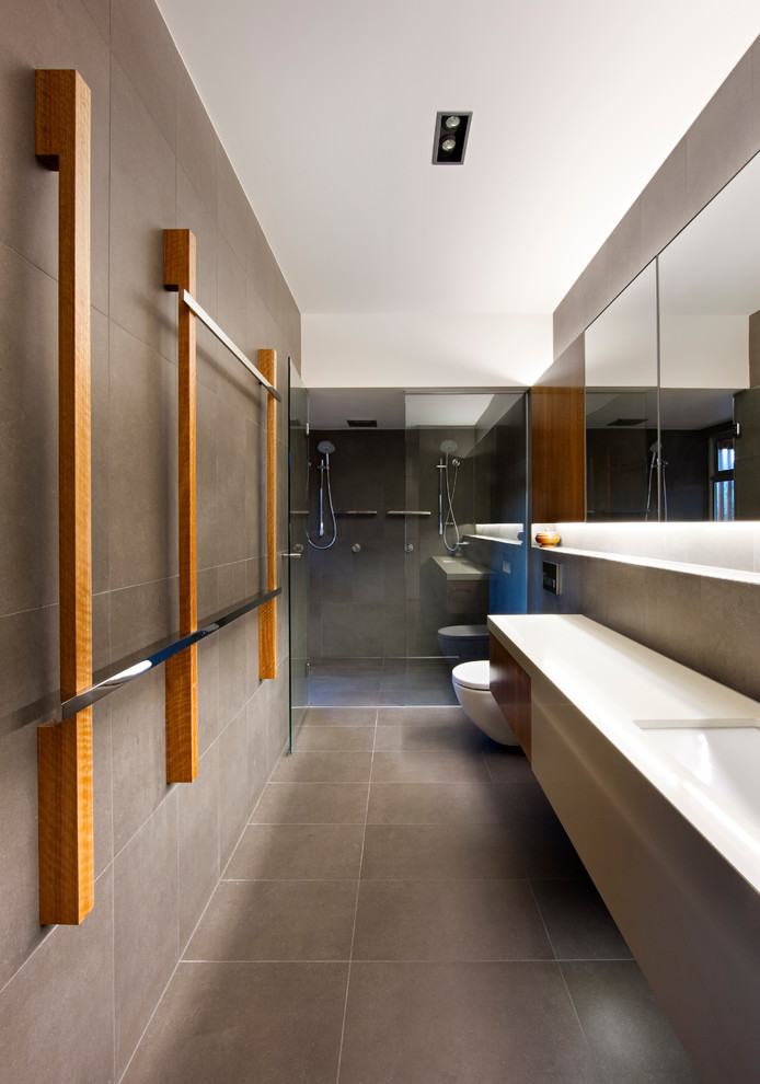 Modelo de cuarto de baño largo y estrecho actual con lavabo bajoencimera, ducha doble, baldosas y/o azulejos grises y paredes grises