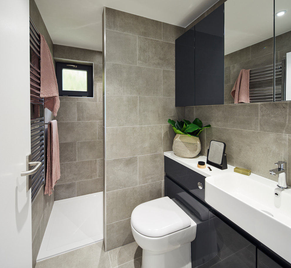Imagen de cuarto de baño contemporáneo con armarios con paneles lisos, puertas de armario negras, ducha empotrada, sanitario de pared, baldosas y/o azulejos grises, paredes grises, aseo y ducha, suelo gris y encimeras blancas