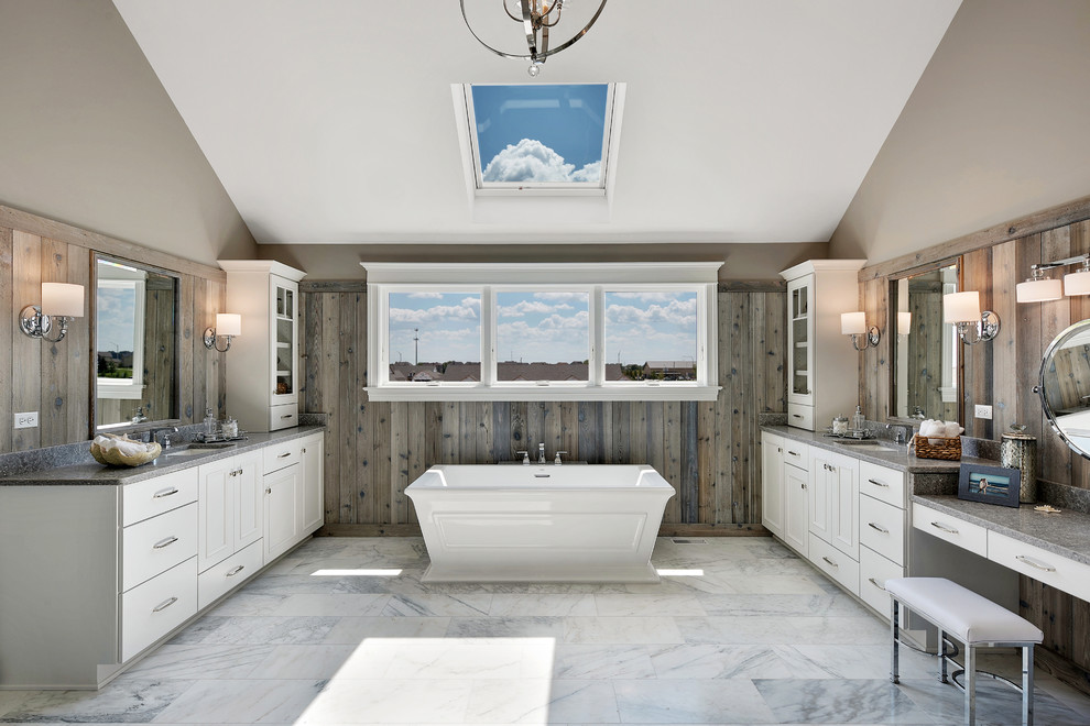 シカゴにあるビーチスタイルのおしゃれなマスターバスルーム (白いキャビネット、置き型浴槽、グレーの壁、大理石の床、アンダーカウンター洗面器、グレーの床、落し込みパネル扉のキャビネット) の写真