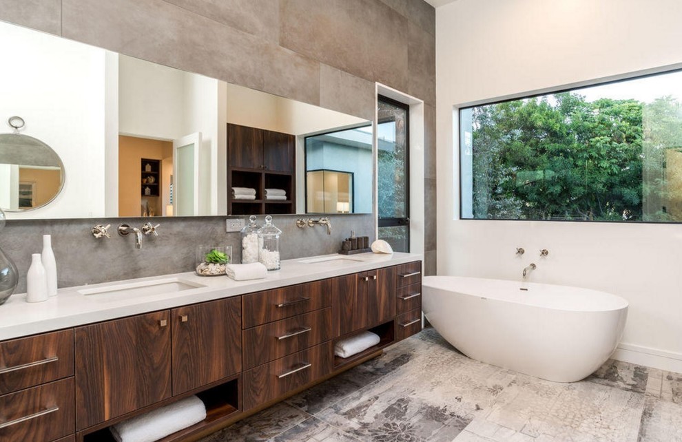 Réalisation d'une salle de bain principale design en bois foncé de taille moyenne avec un placard à porte plane, une baignoire indépendante, un carrelage gris, un mur blanc, un lavabo encastré et un plan de toilette en quartz modifié.