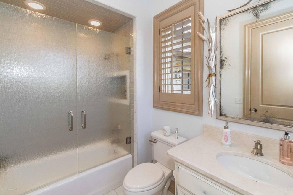Inspiration for a small traditional bathroom in Austin with recessed-panel cabinets, medium wood cabinets, an alcove bath, a shower/bath combination, a one-piece toilet, white tiles, white walls, ceramic flooring, a submerged sink, quartz worktops, white floors and a hinged door.