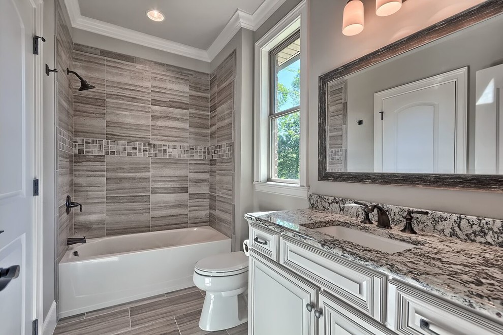 Immagine di una grande stanza da bagno padronale tradizionale con lavabo a consolle, vasca ad alcova, vasca/doccia, piastrelle grigie e pareti grigie