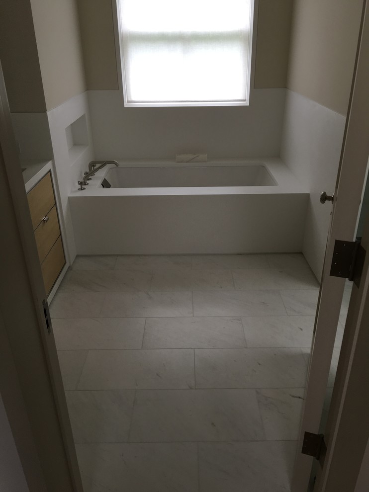 На фото: ванная комната среднего размера в современном стиле с плоскими фасадами, светлыми деревянными фасадами, полновстраиваемой ванной, бежевыми стенами, мраморным полом, душевой кабиной, врезной раковиной и столешницей из искусственного камня с