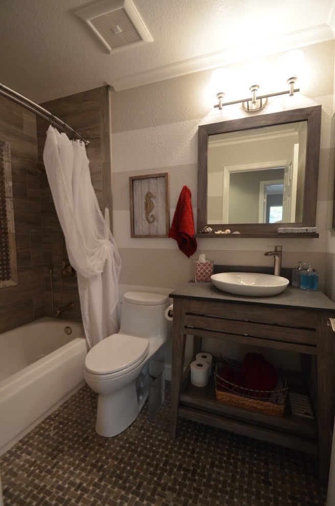 This is an example of a medium sized traditional shower room bathroom in San Francisco with an alcove bath, a shower/bath combination, a one-piece toilet, flat-panel cabinets, distressed cabinets, brown tiles, grey tiles, stone tiles, grey walls, porcelain flooring, a vessel sink and concrete worktops.