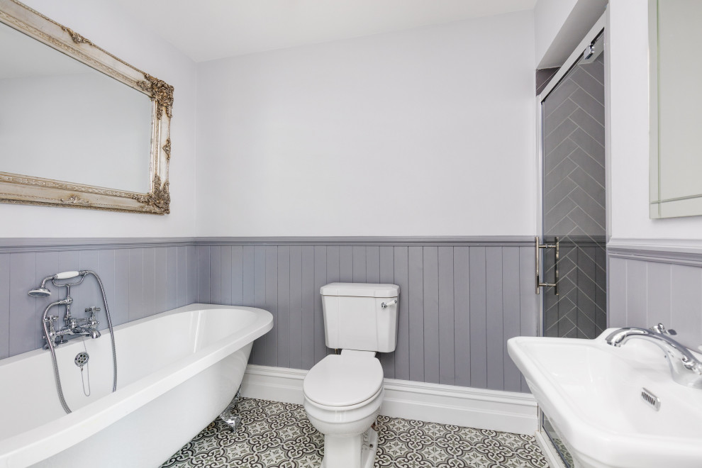 Idéer för att renovera ett mellanstort vintage badrum för barn, med ett fristående badkar, en dusch i en alkov, en toalettstol med separat cisternkåpa, grå kakel, keramikplattor, grå väggar, klinkergolv i keramik, ett piedestal handfat, flerfärgat golv och dusch med gångjärnsdörr