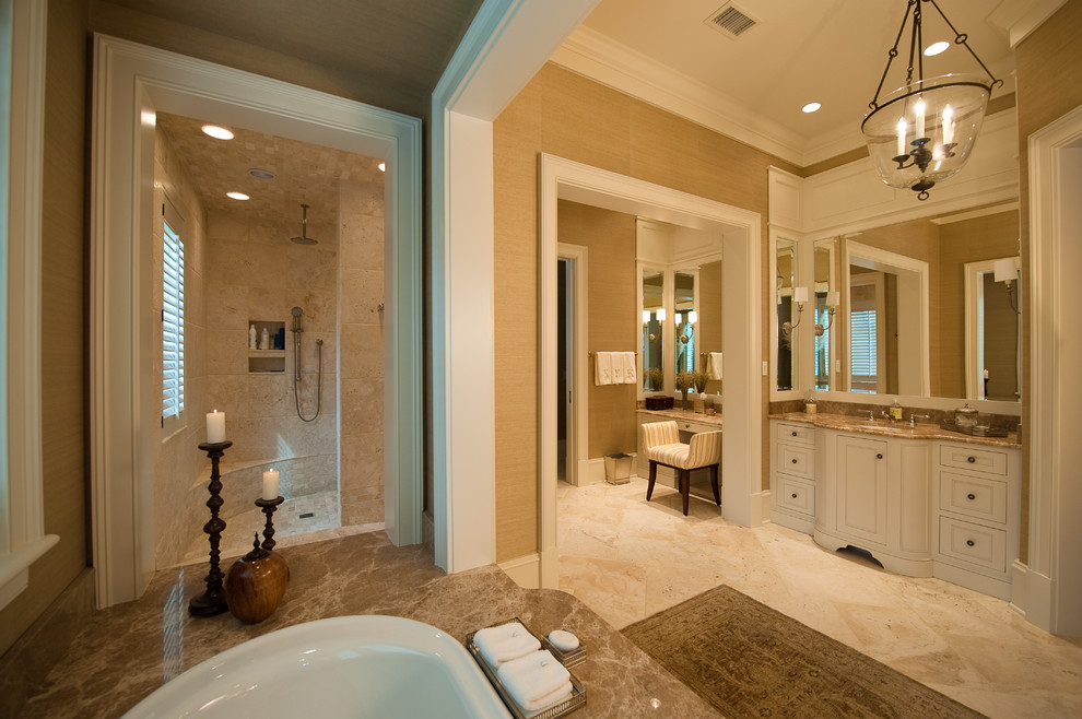 Exemple d'une grande salle de bain principale chic avec un placard avec porte à panneau encastré, des portes de placard blanches, une baignoire posée, une douche d'angle, un carrelage beige, un carrelage de pierre, un mur beige, un sol en marbre, un lavabo encastré et un plan de toilette en marbre.
