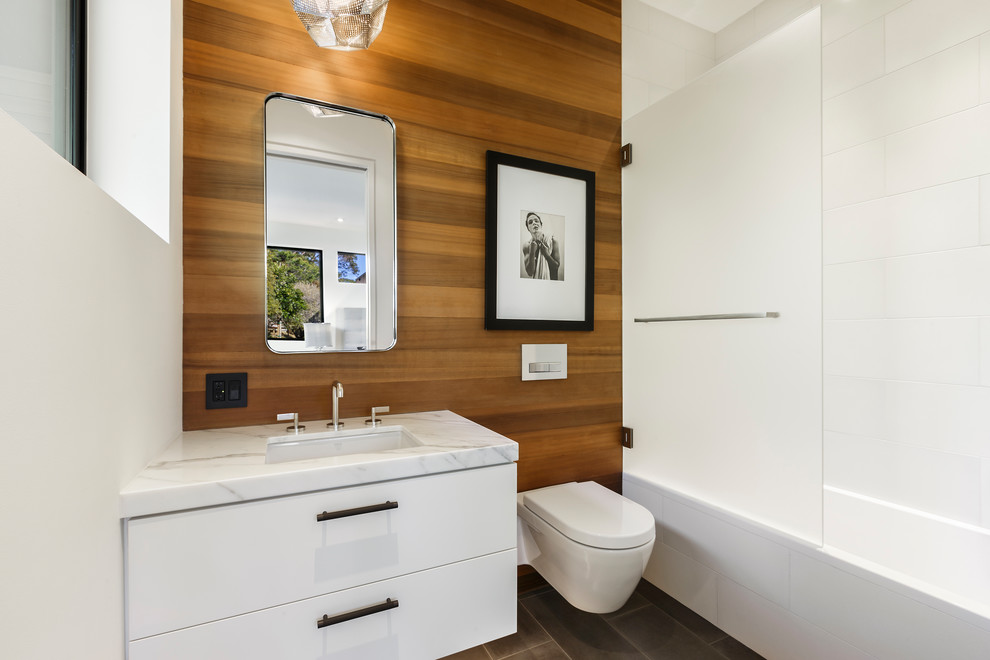 Стильный дизайн: маленькая ванная комната в современном стиле с плоскими фасадами, белыми фасадами, ванной в нише, душем над ванной, инсталляцией, белой плиткой, керамогранитной плиткой, коричневыми стенами, полом из керамогранита, врезной раковиной, мраморной столешницей, серым полом и душем с распашными дверями для на участке и в саду - последний тренд