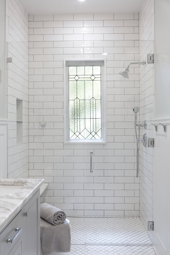 Inredning av ett klassiskt litet vit vitt badrum, med skåp i shakerstil, grå skåp, en kantlös dusch, en toalettstol med separat cisternkåpa, vit kakel, tunnelbanekakel, grå väggar, cementgolv, ett undermonterad handfat, marmorbänkskiva, vitt golv och dusch med gångjärnsdörr