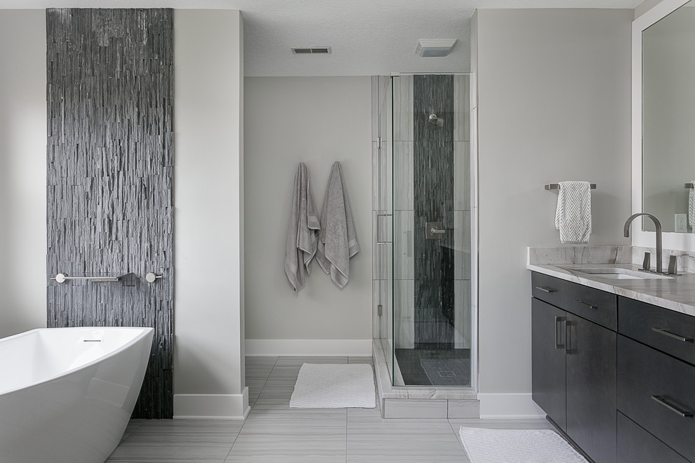 Inspiration for a medium sized modern ensuite bathroom in Other with flat-panel cabinets, dark wood cabinets, a freestanding bath, a walk-in shower, a two-piece toilet, ceramic flooring, a submerged sink, quartz worktops, grey floors and a hinged door.