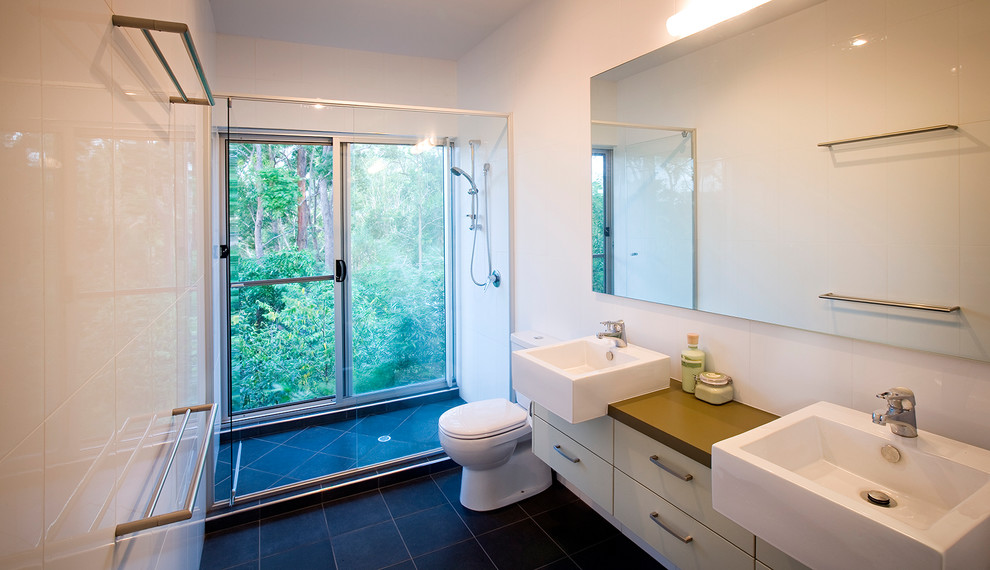 Inredning av ett modernt mellanstort badrum med dusch, med ett piedestal handfat, släta luckor, vita skåp, en dubbeldusch, vit kakel, vita väggar och en toalettstol med separat cisternkåpa
