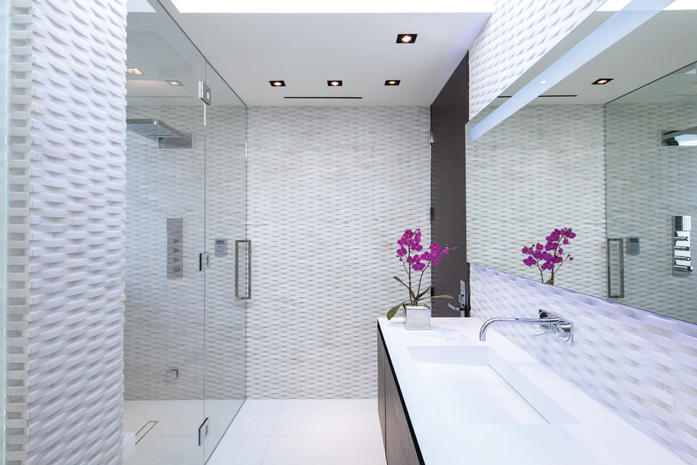 Inredning av ett modernt mellanstort badrum, med släta luckor, skåp i mörkt trä, en kantlös dusch, vit kakel, ett integrerad handfat, vitt golv och dusch med gångjärnsdörr