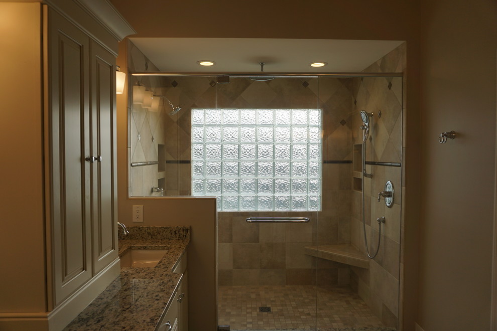 Exemple d'une grande douche en alcôve principale chic avec un plan de toilette en granite, un placard avec porte à panneau surélevé, des portes de placard beiges, un carrelage beige, un mur beige et un lavabo encastré.