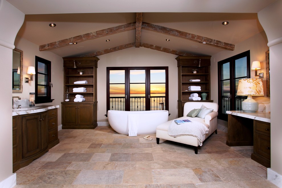 Exempel på ett mellanstort medelhavsstil en-suite badrum, med luckor med upphöjd panel, skåp i mellenmörkt trä, ett fristående badkar, beige väggar, klinkergolv i keramik, ett undermonterad handfat, marmorbänkskiva och beiget golv